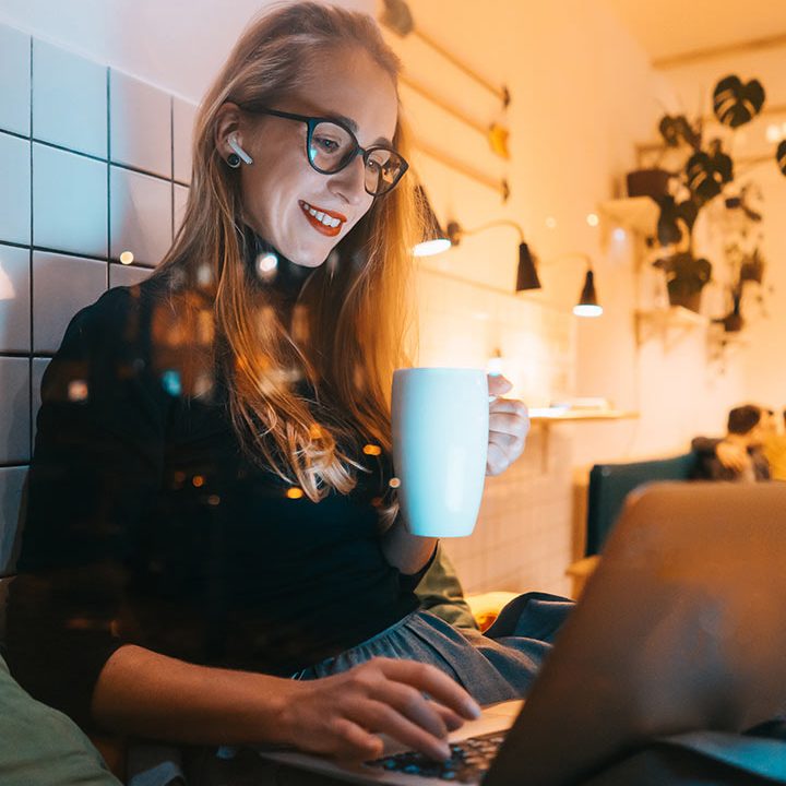 A woman sitting at a table with a laptop and cup.