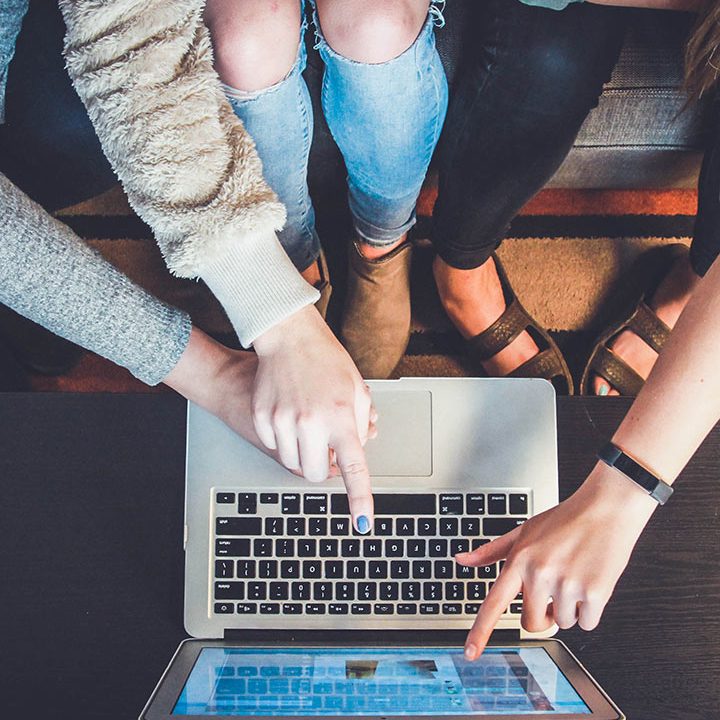 A group of people standing around a laptop.