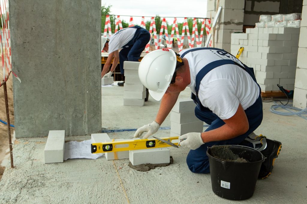 A construction worker measuring the wall of a building.