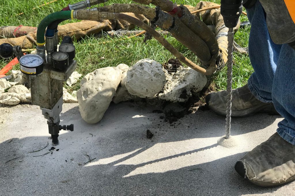 A drill and some rocks on the ground