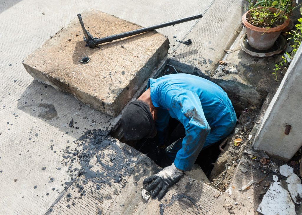 A man in blue shirt digging into hole.