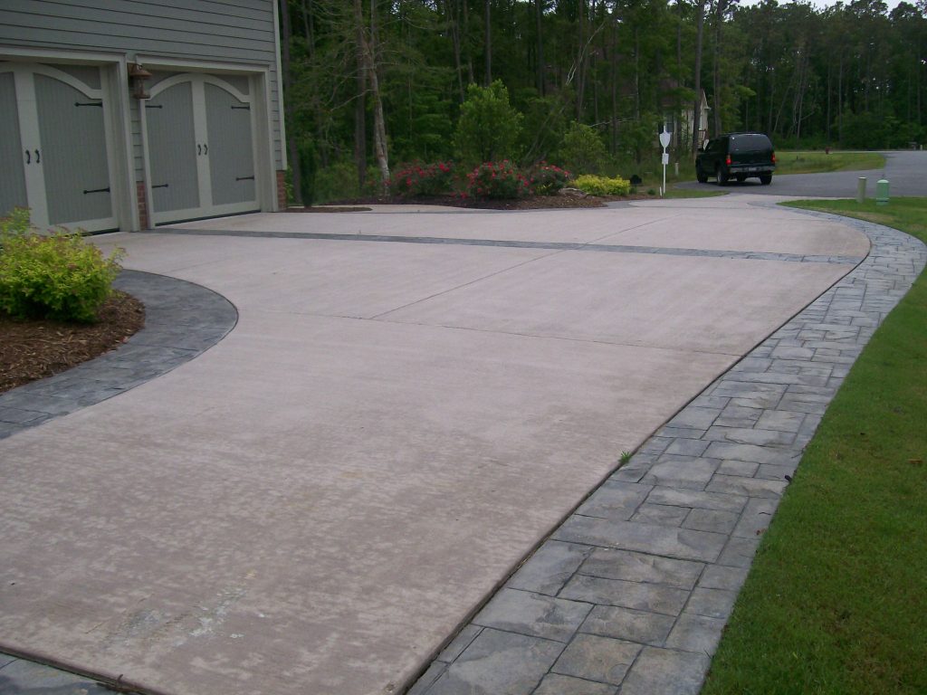 A driveway with a large concrete slab and a brick border.