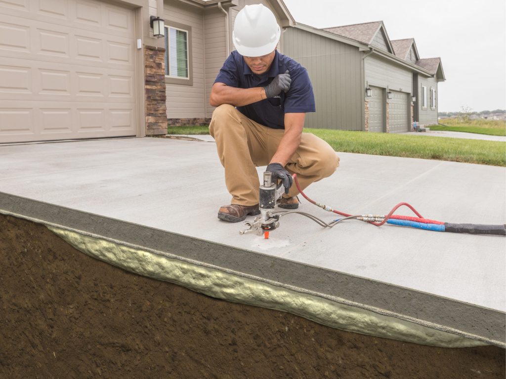 A man kneeling down on the ground with a drill.