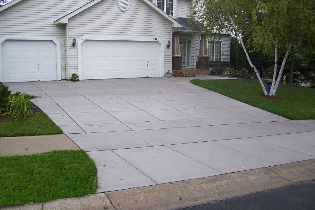 A driveway with grass and trees in front of it.