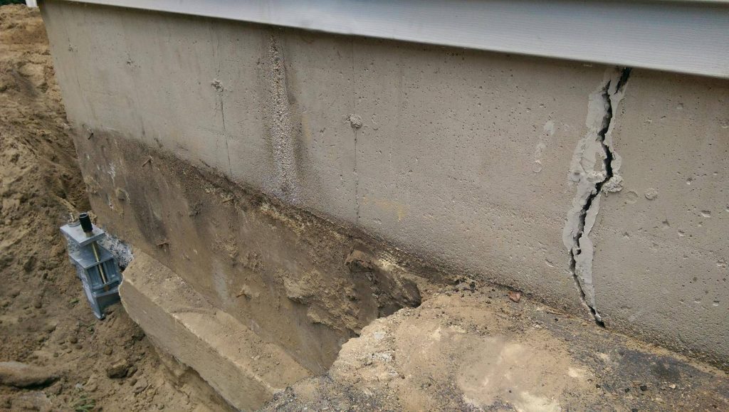 A concrete wall with holes in it and some dirt