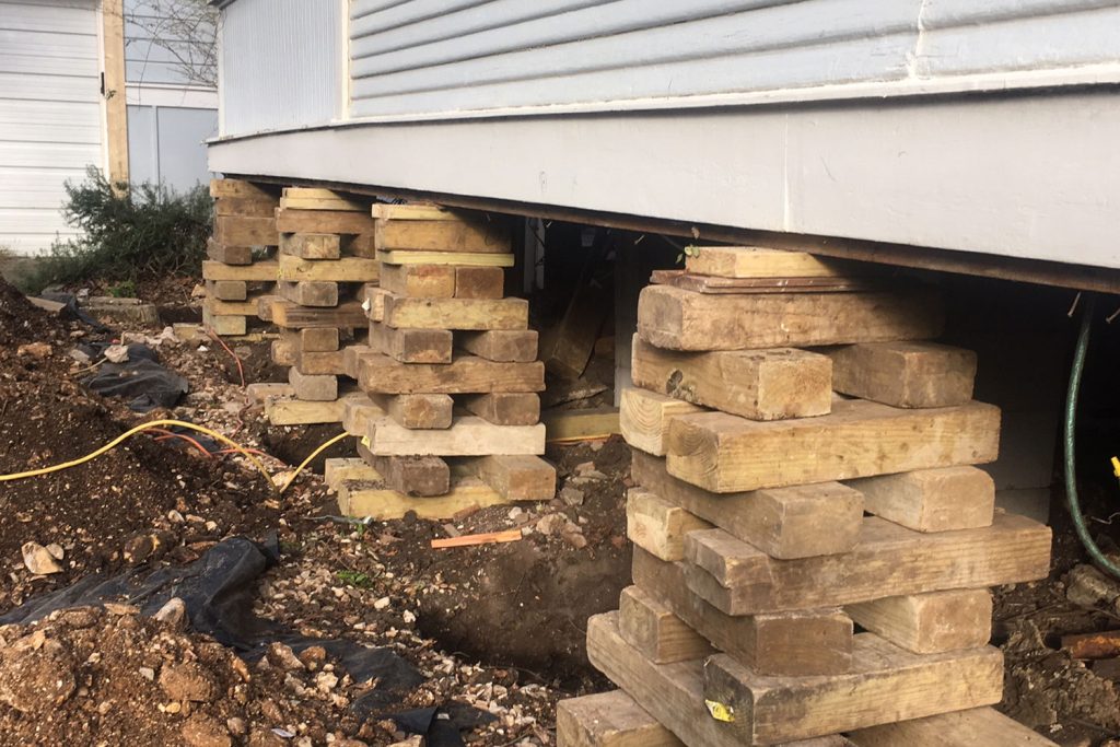 A house with many piles of wood in the ground.