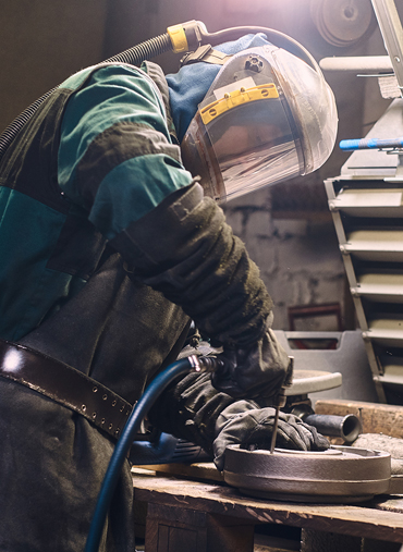 A man wearing protective gear working on metal.