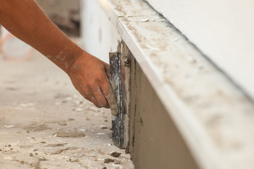 A person using a hand tool to cut the wall.