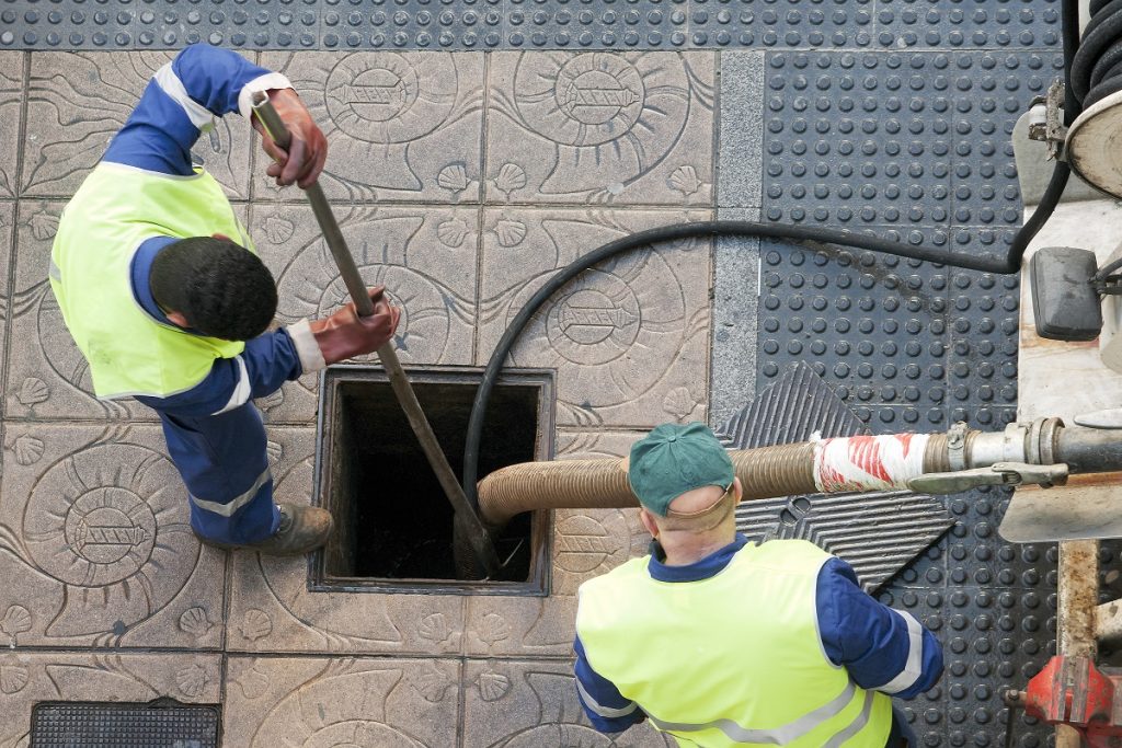 Two men are working on a hole in the wall.