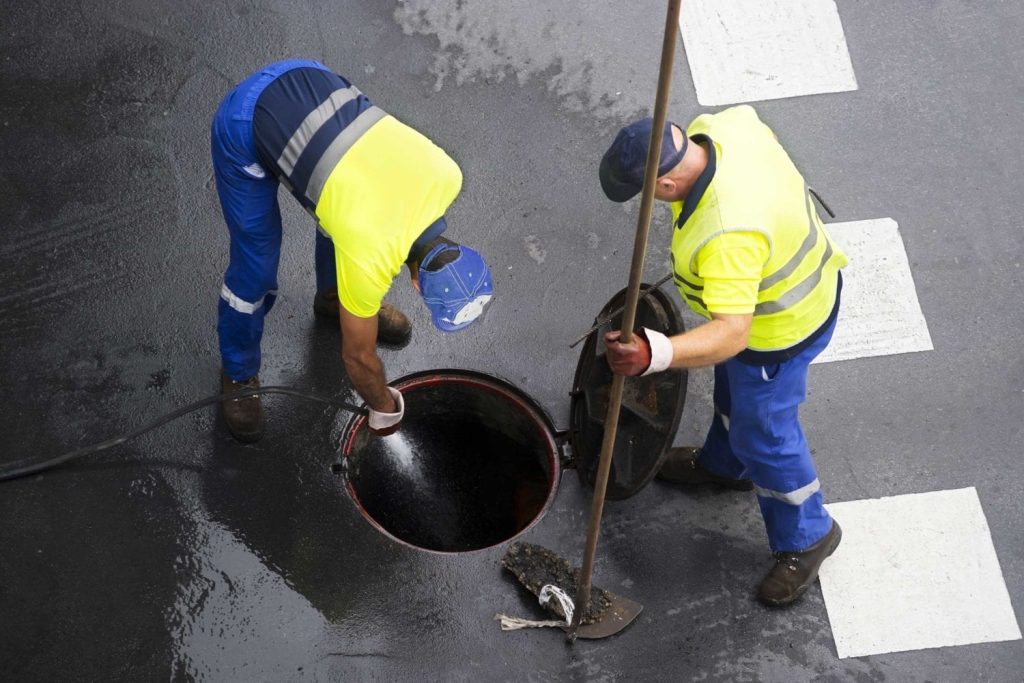 Two men are working on a street.