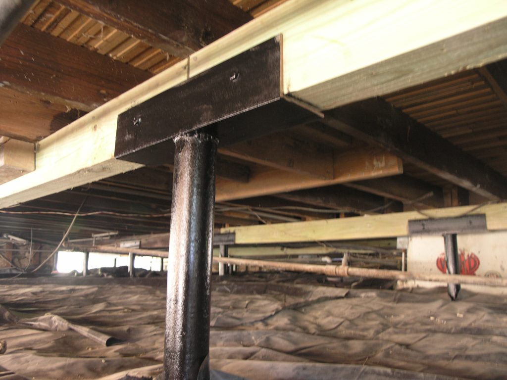 A large metal pole under a building with some rocks.