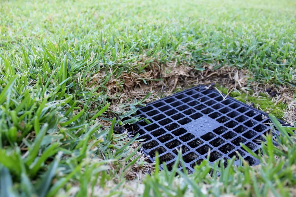 A black grate in the middle of grass.