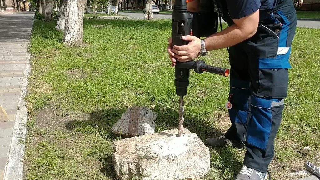 A man using an electric drill to hole into the ground.