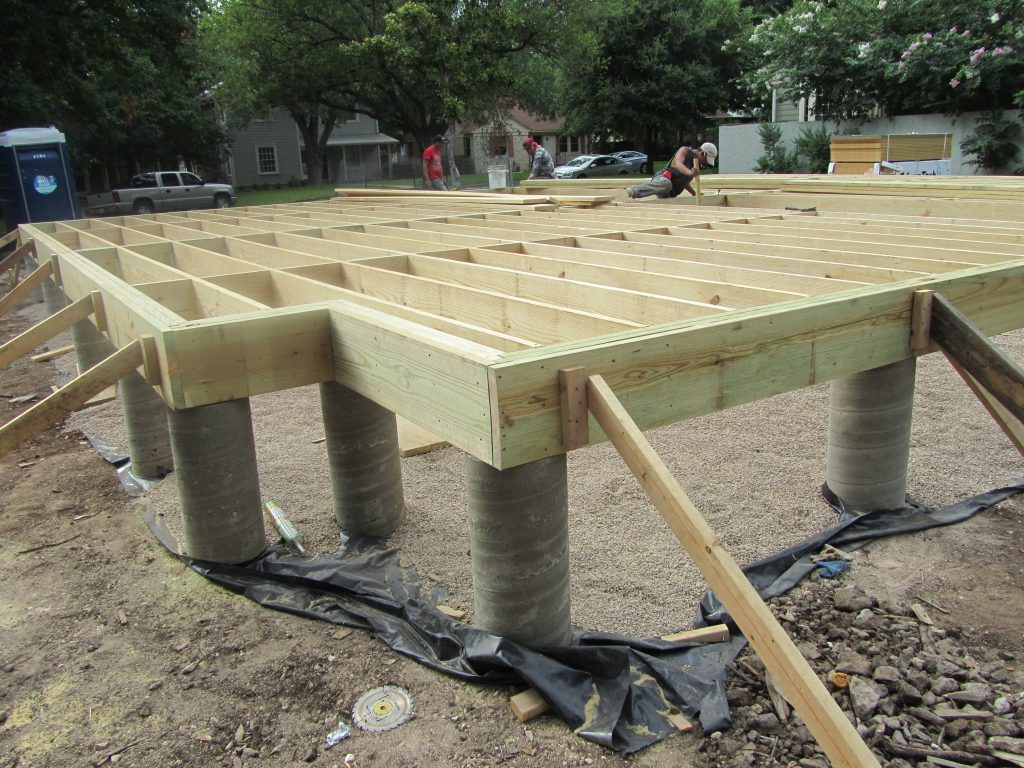 A wooden structure being constructed with concrete pillars.