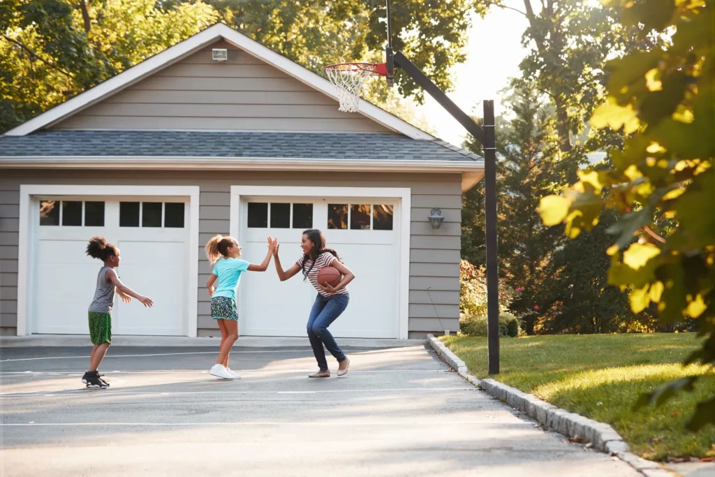 A group of people playing frisbee in front of a garage.