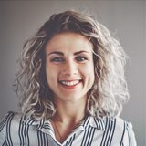 A woman with curly hair smiling for the camera.